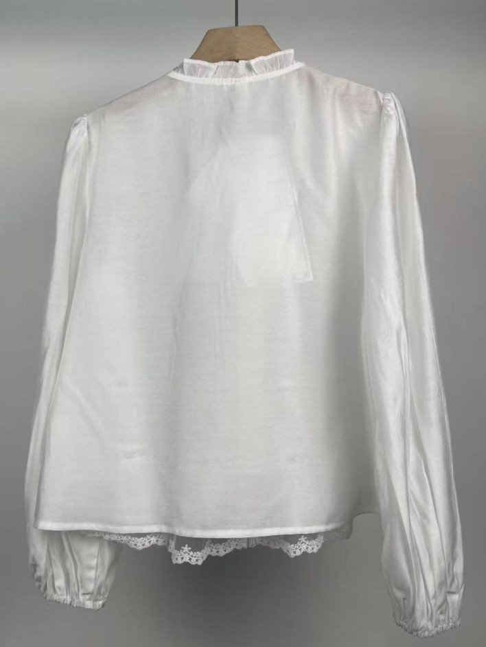White Tiered Ruffle Collar Blouse in white. Macro close-up view focusing on the White tiered blouse with ruffled collar and lace-like trim. B2B wholesale Blouses & Tops SKU: AM261086.