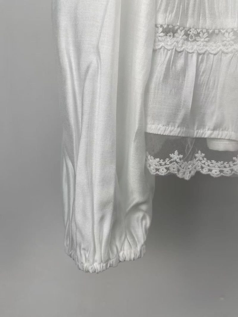 White Tiered Ruffle Collar Blouse in white. Macro close-up view focusing on the White tiered blouse with ruffled collar and lace-like trim. B2B wholesale Blouses & Tops SKU: AM261086.